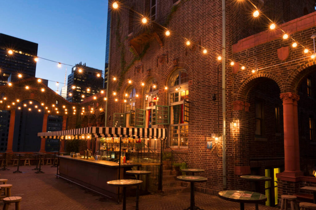 Rooftop bar at Artie’s Backroom & Rooftop in Murray Hill NYC with city lights at night